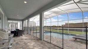 A covered patio with a barbecue area, a pool, and a view of a backyard. - Non-renting - 1533fd - The Retreat at Championsgate (Davenport)