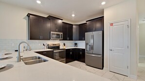 A modern kitchen with dark cabinets, stainless steel appliances, and a white countertop. - Non-renting - 1533fd - The Retreat at Championsgate (Davenport)