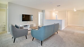 A modern living room with a flat-screen TV, two sofas, a coffee table, and a white entertainment unit. - Non-renting - 1533fd - The Retreat at Championsgate (Davenport)