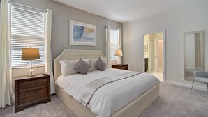 A bedroom with a large bed, two bedside tables with lamps, a painting on the wall, and a mirror on the wall. - Non-renting - 1533fd - The Retreat at Championsgate (Davenport)