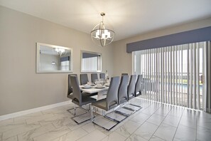 A dining area with a long table, chairs, and a chandelier. - Non-renting - 1533fd - The Retreat at Championsgate (Davenport)