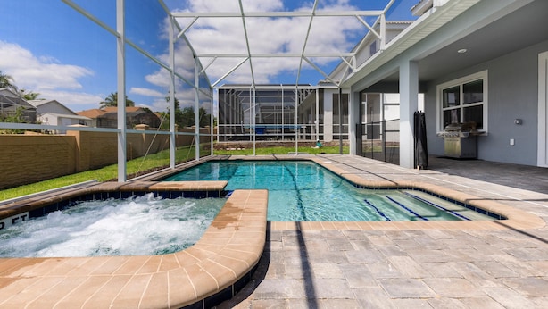 Una piscina con un jacuzzi, rodeada por una zona de patio techada.