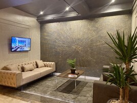 Una sala de estar moderna con un sofá, una mesa de centro, un televisor y una decoración de pared.