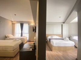 Una habitación de hotel moderna con dos camas, un escritorio con una computadora portátil, una cafetera y un televisor montado en la pared.
