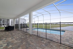 Un patio couvert avec une piscine, des sièges d’extérieur et une vue sur un terrain de golf.