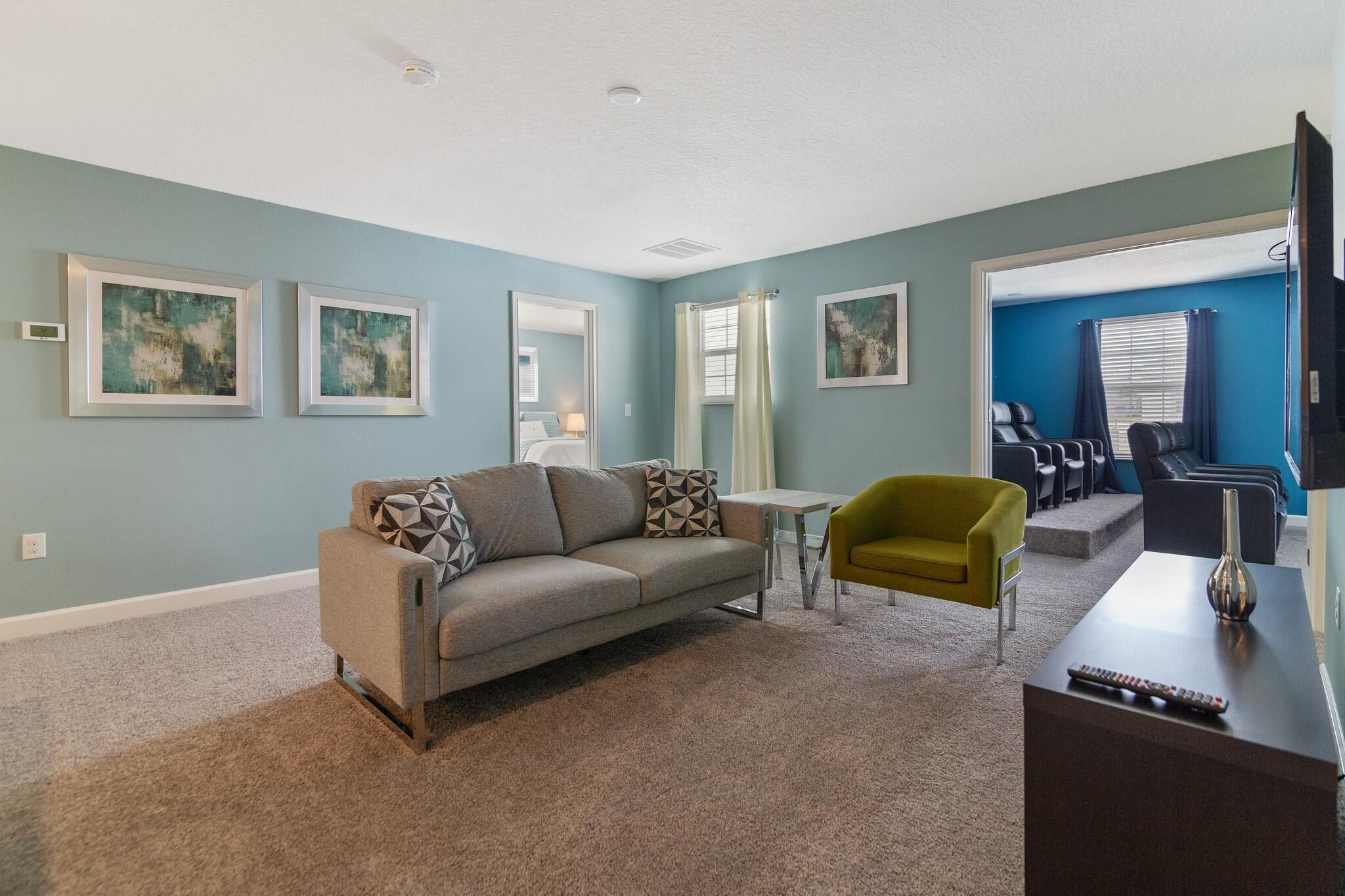 A living room with a sofa, a small table, a yellow armchair, and a TV.