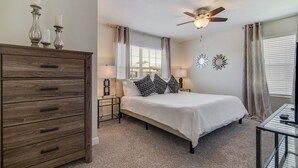 Ein Schlafzimmer mit Bett, Schminktisch, Nachttischlampen, Deckenventilator und dekorativen Wandspiegeln.