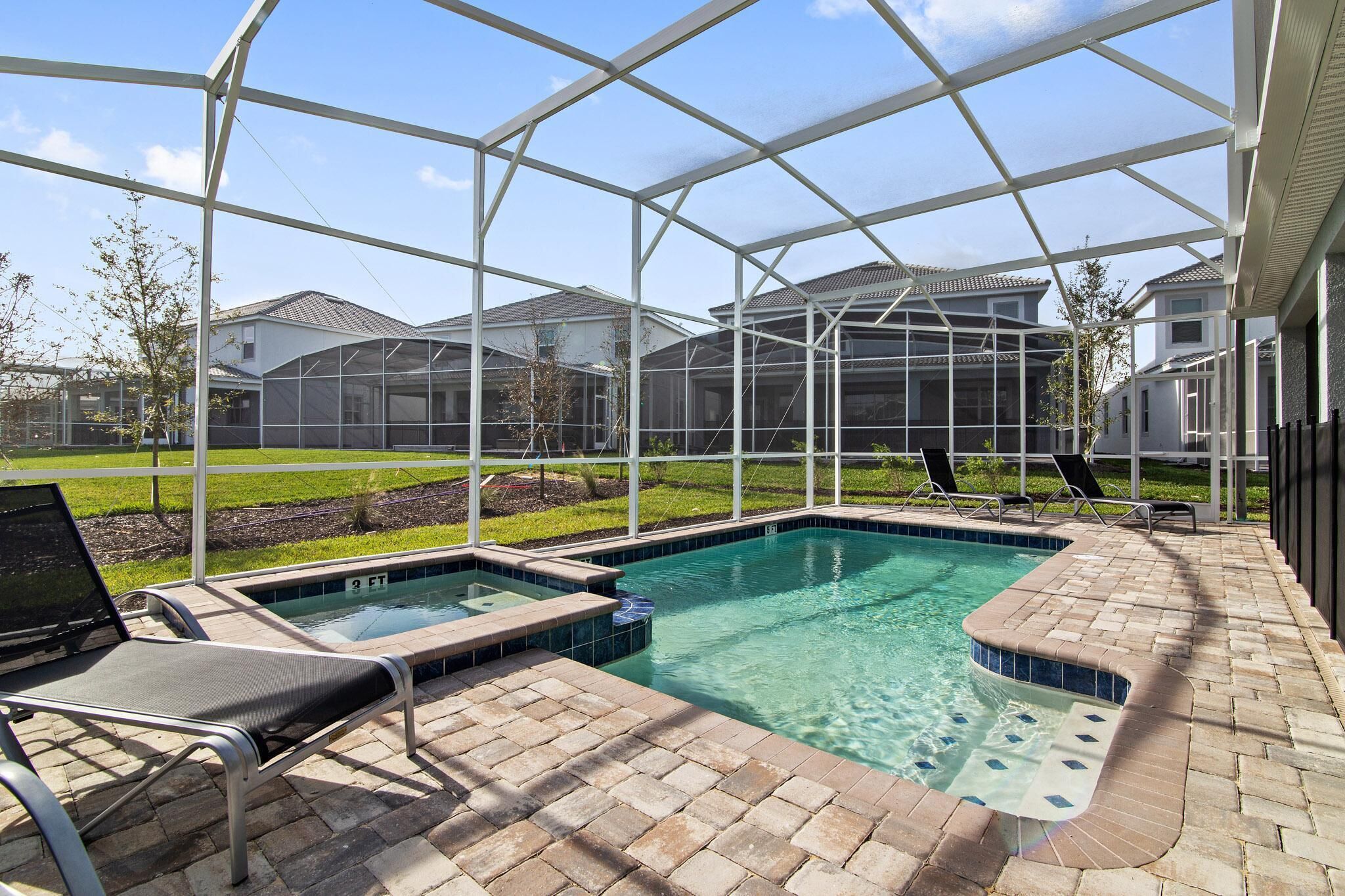 A covered outdoor swimming pool with lounge chairs and a laptop on the deck.