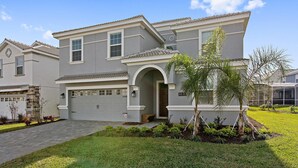 A two-story house with a garage, a well-maintained lawn, and a small palm tree. - 8830ilc - The Retreat at Championsgate (Davenport)