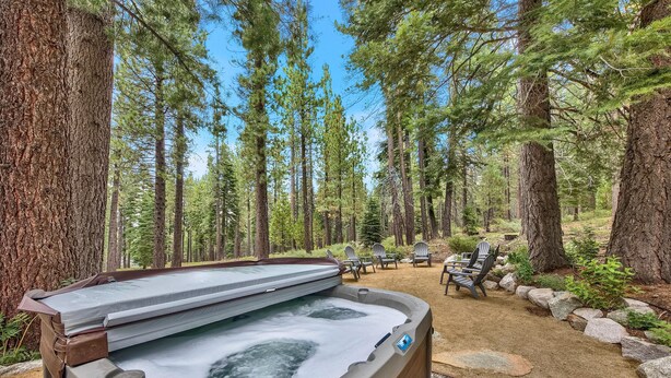 Un jacuzzi en un área boscosa, con sillas y una fogata.