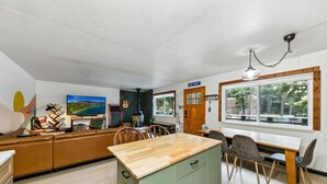 Una cocina moderna con una isla de madera, armarios verdes y un comedor con sillas y una mesa.