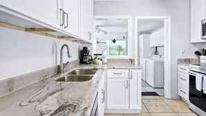 A modern kitchen with white cabinetry, a marble countertop, and stainless steel appliances.