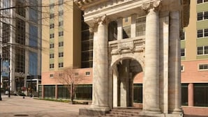 A building entrance with a classical archway and columns, featuring the name "MILTON" on the arch. - Conveniently Located Downtown Apartment (Atlanta)