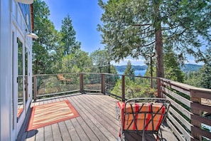 A wooden deck with a red rug, a chair, and a view of trees and mountains. - ‘Lakeview Lodge’ Fit for Groups < 1 Mile to Lake! (Lake Arrowhead)