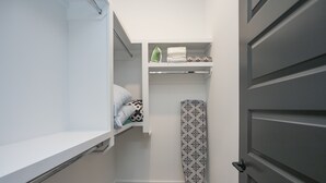 A compact bathroom with a shower, a toilet, and a sink. There is a towel rack with folded towels and a shower curtain.