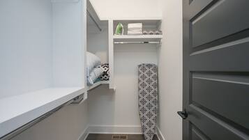 A compact bathroom with a shower, a toilet, and a sink. There is a towel rack with folded towels and a shower curtain.