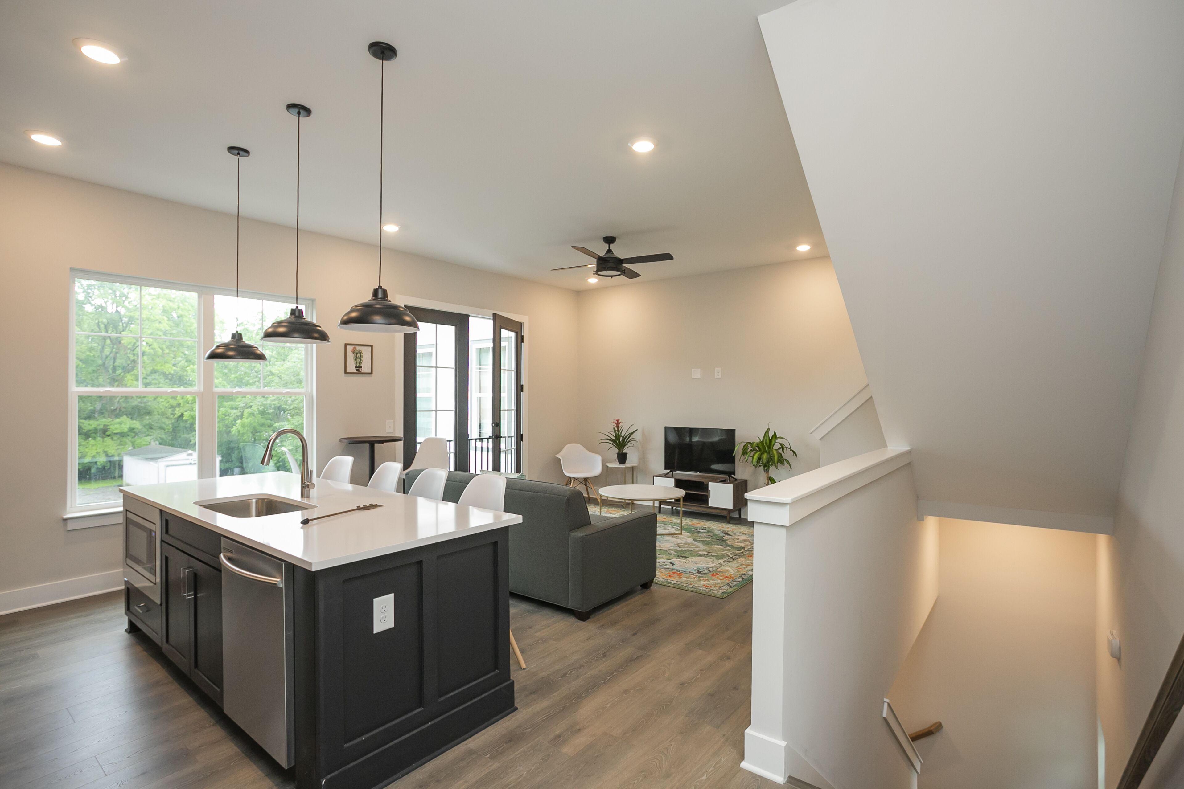 A modern kitchen with a large island, dark cabinetry, and pendant lighting.
