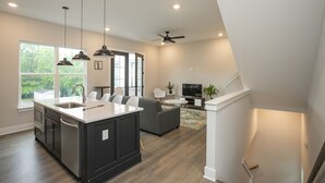 A modern kitchen with a large island, dark cabinetry, and pendant lighting.