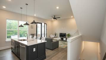 A modern kitchen with a large island, dark cabinetry, and pendant lighting.