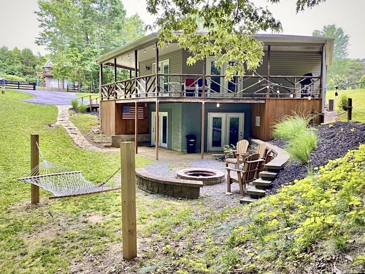 A two-story building with a covered deck, a fire pit, outdoor seating, and a hammock.