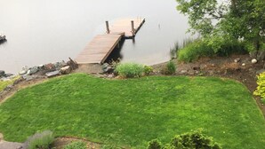Un jardin bien entretenu avec une jetée en bois qui s’avance sur un lac paisible.