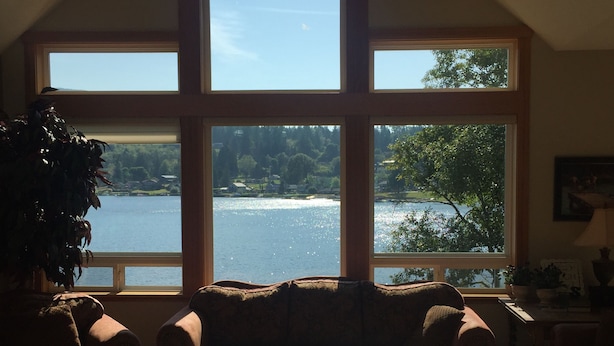 Un salon doté d’une grande fenêtre donnant sur un lac, d’un canapé et d’une table basse.