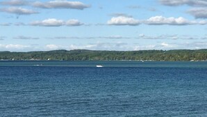Une vue d’une vaste étendue d’eau, avec des bateaux et une côte lointaine bordée d’arbres.