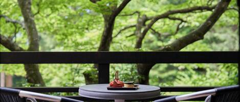 A round table with a tray containing a red bag and a small item, set against a backdrop of lush greenery.