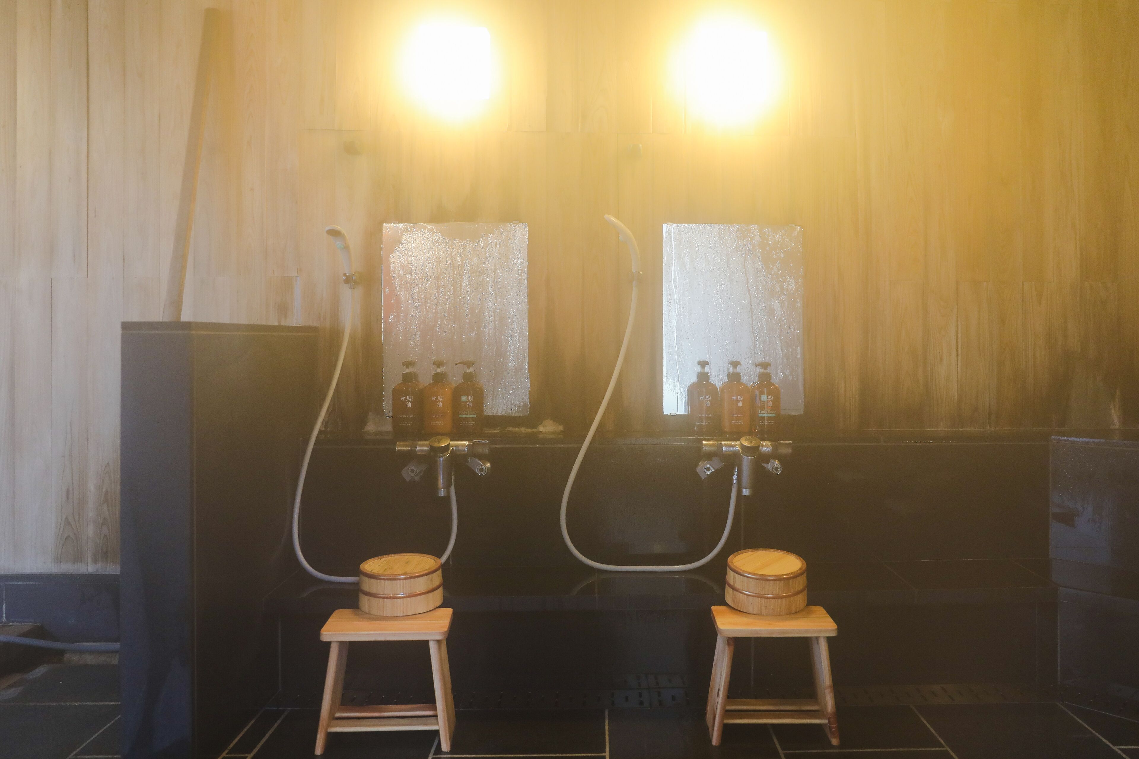 Una sala de sauna con dos bancos de madera, dos espejos grandes y dos botellas de aceite en la pared.