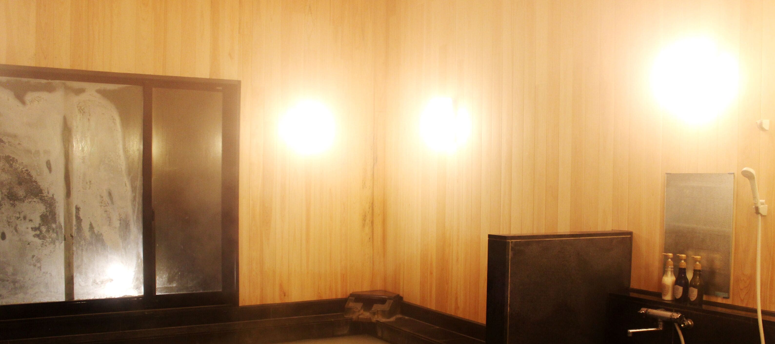A wooden interior with a large mirror, a sink, and a small trash bin.