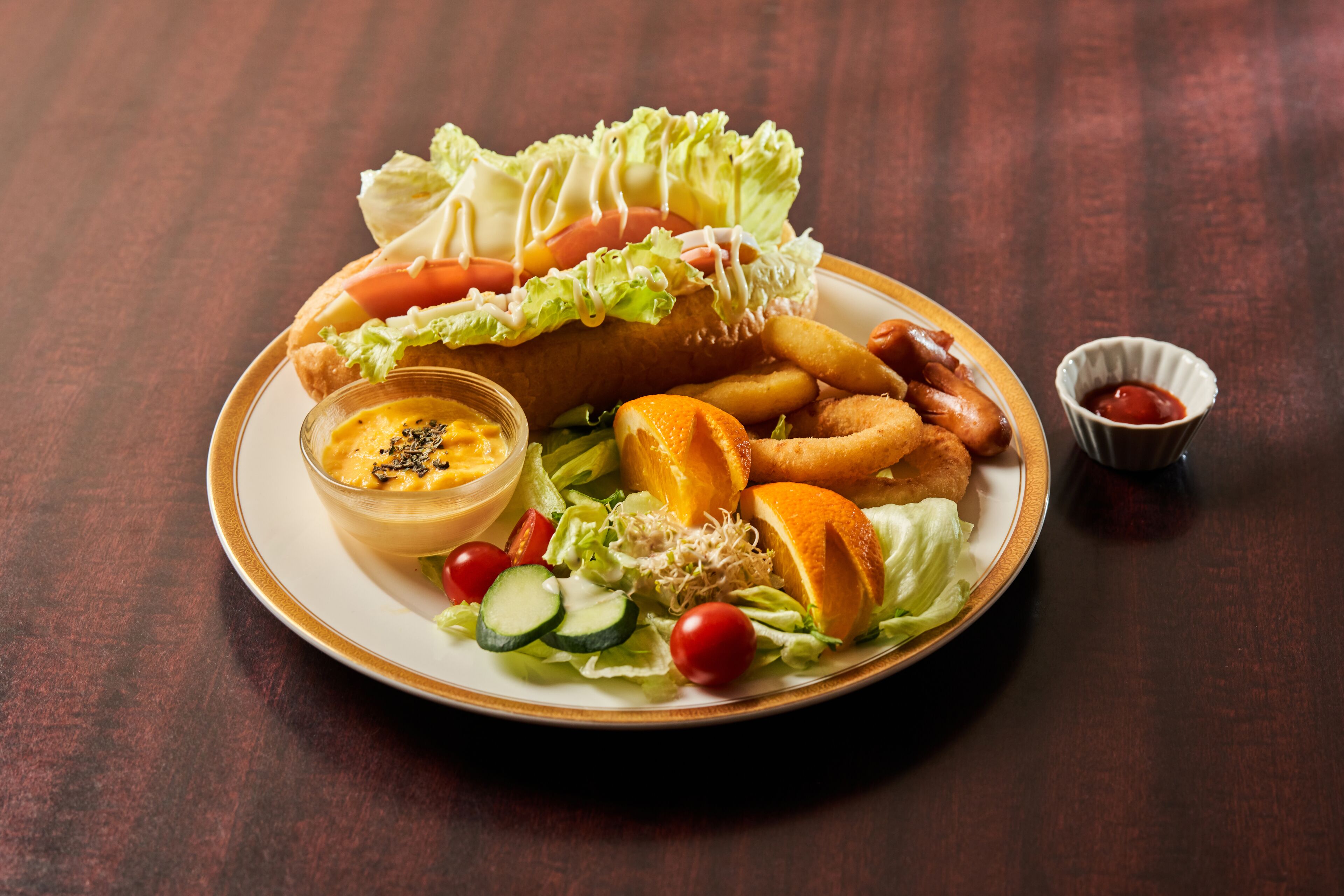 Un plato de comida que incluye un sándwich, papas fritas y un pequeño recipiente con salsa.