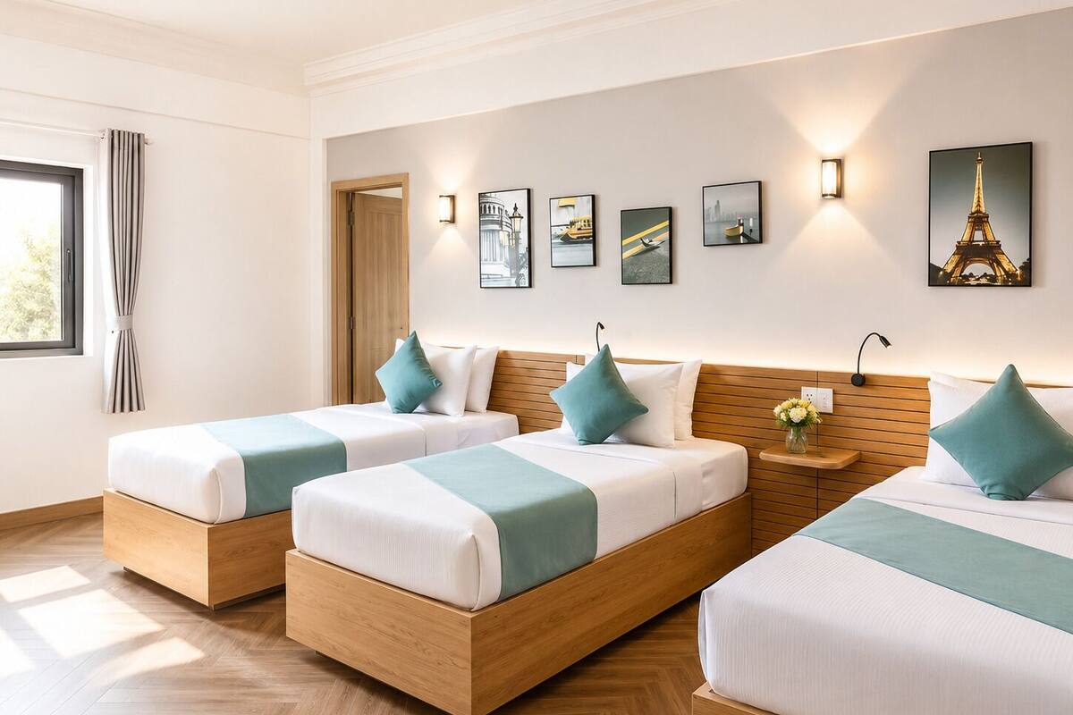Une chambre d’hôtel avec deux lits, une tête de lit en bois, une table de chevet ornée d’un vase de fleurs et des œuvres d’art accrochées au mur.