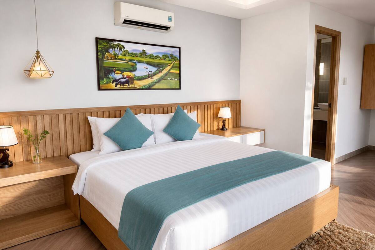 Une chambre à coucher avec une tête de lit en bois, un lit avec une literie blanche et des touches de couleur turquoise, une table de chevet avec une lampe et un climatiseur fixé au mur.