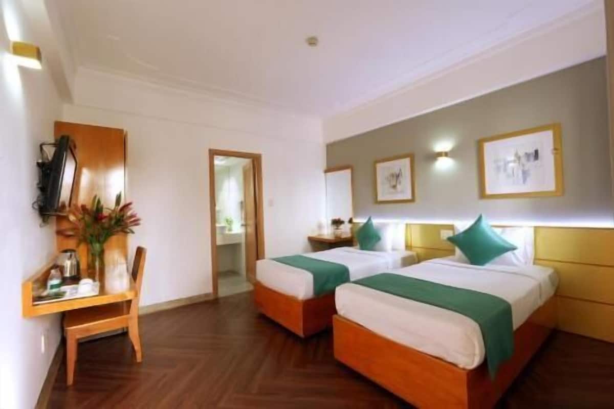 Une chambre d’hôtel avec deux lits, un bureau et une chaise.