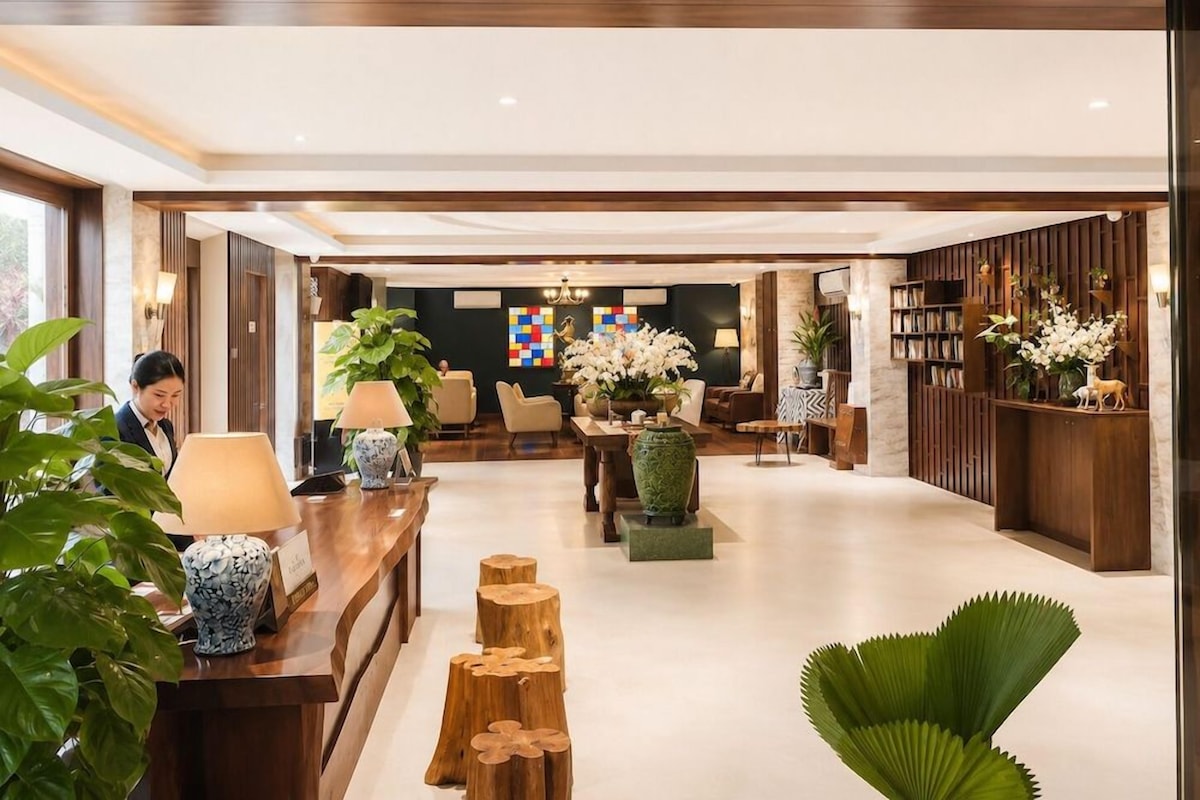 Un hall d’hôtel comprenant un comptoir d’accueil, un espace salon et une bibliothèque.