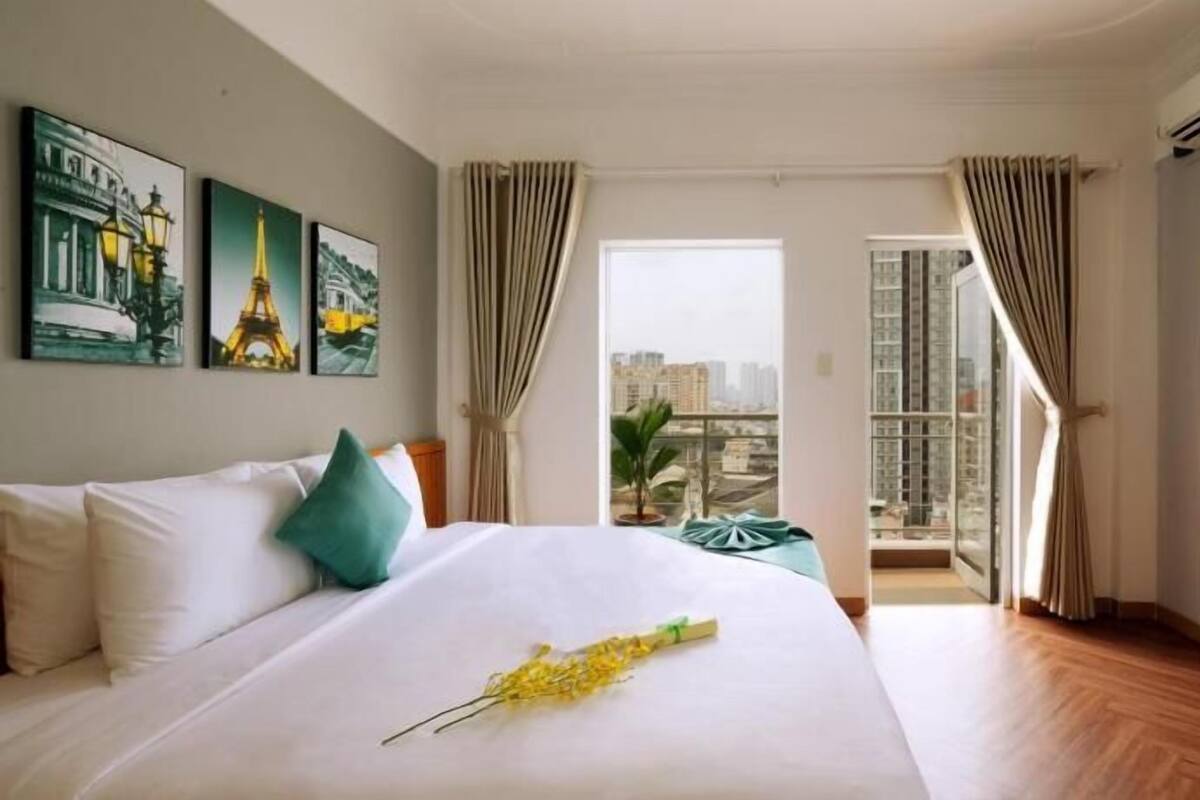 Une chambre d’hôtel avec un lit, un bureau, une chaise et une vue sur le paysage urbain.