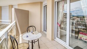 Un balcon avec une table ronde, des chaises et une vue sur la ville, grâce à de grandes fenêtres.