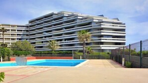 Un immeuble moderne à plusieurs étages, avec une piscine en premier plan.