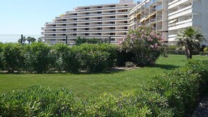 Un hôtel moderne à plusieurs étages, doté de balcons, entouré d’un espace verdoyant bien entretenu et offrant une vue sur un ciel dégagé.