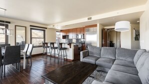 Ein modernes Wohnzimmer mit einem grauen Sofa, einem Holztisch und einem Essbereich mit Stühlen und einem Tisch.