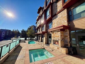 A pool area with a stone wall, a fire feature, and a clear sky. - Ski-In/Out in Park City Village|Heated Pool|Hot Tub|Managed by Park City Lodging (Park City)