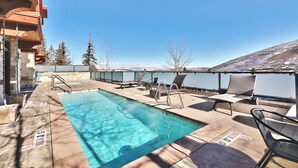 A pool area with lounge chairs and a view of mountains. - Managed by Park City Lodging-Hotel Room Ski-In/Out-Park City Mtn-Hot Tub/Pool (Park City)