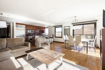 Comfortable living room with two lounge chairs, large coffee table with the dining and kitchen area in the background