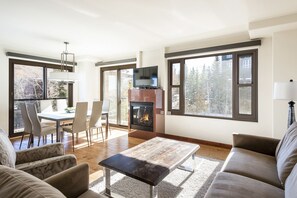 Un salon spacieux doté d’une cheminée, de grandes fenêtres et d’un coin repas.