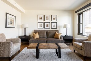 Una sala de estar moderna con un conjunto de sofás, una mesa de centro y cuadros en la pared.