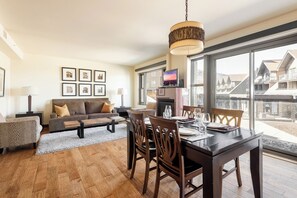Un salon moderne avec un canapé, une table à manger dressée pour quatre personnes et un téléviseur.