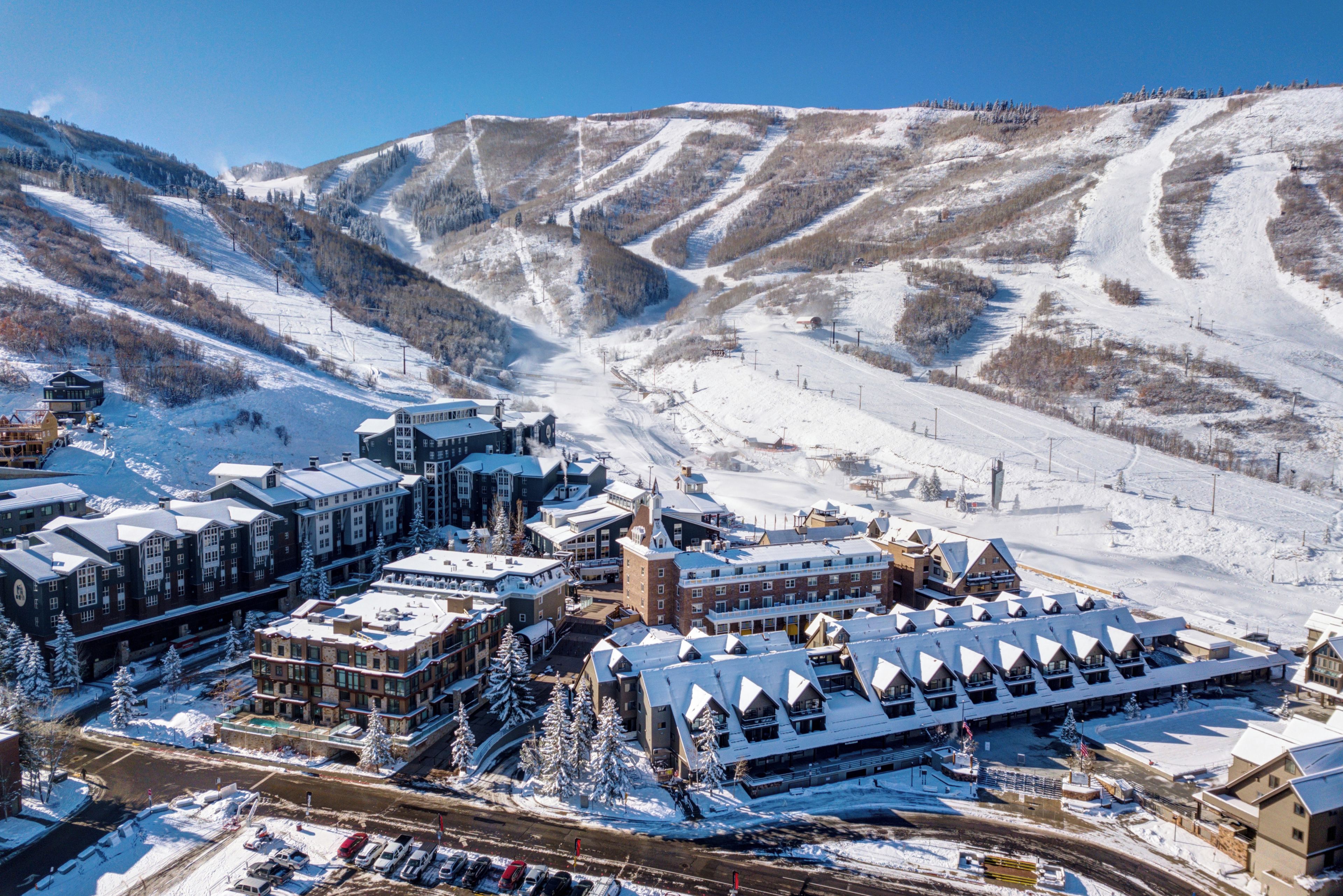 Une ville enneigée avec une station de ski, comprenant des bâtiments aux toits couverts de neige et un télésiège en arrière-plan.