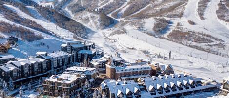 A snow-covered town with a ski resort, including buildings with snow-covered roofs and a ski lift in the background.