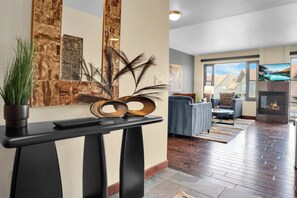 A modern living room with a fireplace, a large window with a mountain view, and a console table with decorative items.