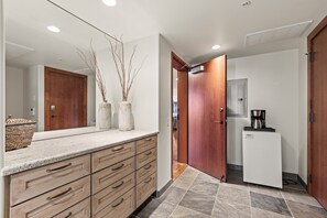 Una cocina moderna con refrigerador incorporado, cafetera y un espejo grande sobre la encimera.